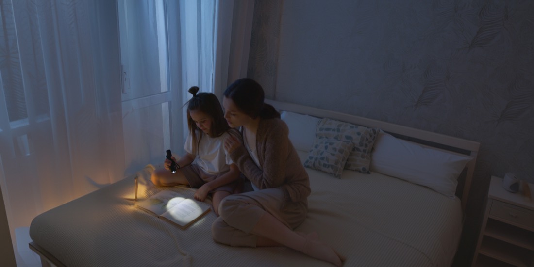 Mother and child reading by flashlight during a power outage