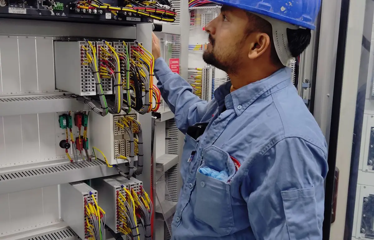 Electrician working inside a commercial electrical control panel